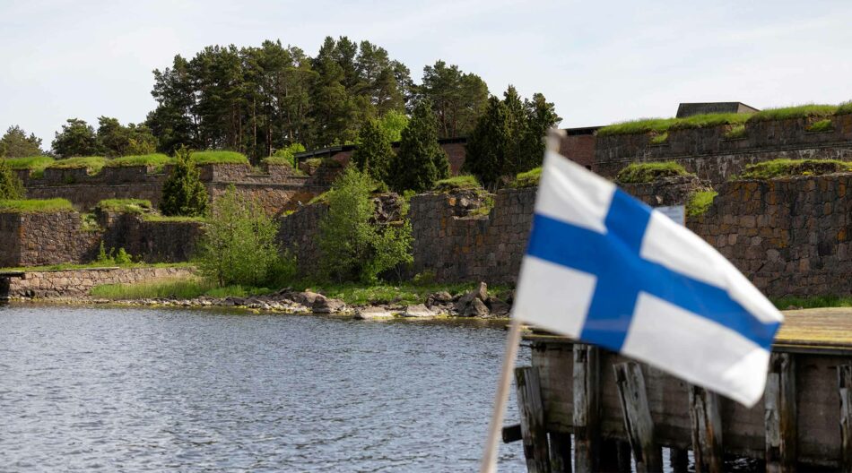 Suomen lippu ja taustalla kivilinnoitus